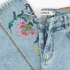 Pantaloni jeans con impunture a fiori